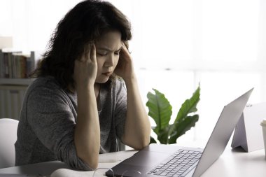 Yorgun ve stresli hissediyorum. Genç Asyalı iş kadını ev ofisinde dizüstü bilgisayar kullanarak çalışırken yorgunluk ve yorgunluktan gözleri kapalı oturuyor. Çalışmaktan yorgun düşmüş Asyalı bayan öğrenci göz ve şakaklara masaj yapıyor.