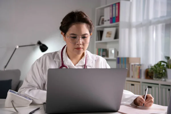 아름다운 아시아 의사가 사무실에서 노트북 컴퓨터를 가지고 일하고 환자와 온라인 — 스톡 사진