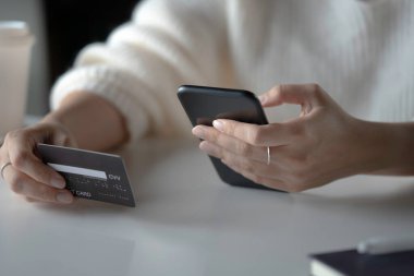 Kadın eli kredi kartı tutuyor ve akıllı telefon kullanıyor. İnternetten alışveriş