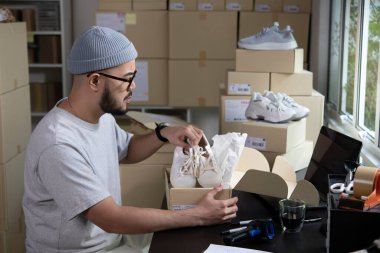 Asyalı bir işletme sahibi, müşteriye sevkiyat siparişini hazırlıyor. Erkek girişimci ambalaj kutusu depoya teslim edilecek..