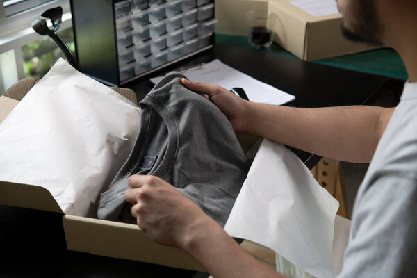 Male online store small business owner entrepreneur packing package post shipping box preparing delivery parcel on table. E-commerce drop shipping shipment service concept.                                                                              