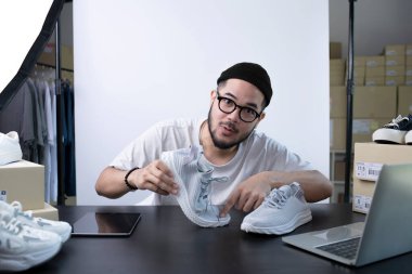 Çekici Asyalı blog yazarı ya da video blogcusu ürünü inceleyen kameraya bakıyor. Modern iş adamı pazarlama için sosyal medyayı kullanıyor. Sosyal medya kavramı üzerinde iş çevrimiçi etkileyiciName.