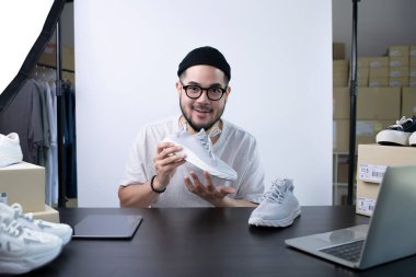 Çekici Asyalı blog yazarı ya da video blogcusu ürünü inceleyen kameraya bakıyor. Modern iş adamı pazarlama için sosyal medyayı kullanıyor. Sosyal medya kavramı üzerinde iş çevrimiçi etkileyiciName.