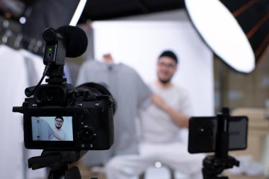 Çekici Asyalı blog yazarı ya da video blogcusu ürünü inceleyen kameraya bakıyor. Modern iş adamı pazarlama için sosyal medyayı kullanıyor. Sosyal medya kavramı üzerinde iş çevrimiçi etkileyiciName.