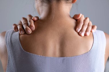 Asyalı kadının omuz ağrısı var. Başka bir elle ağrılı omuz tutan bir kadın. Vücut-kas problemi, sağlık ve ilaç sorunları olan insanlar..