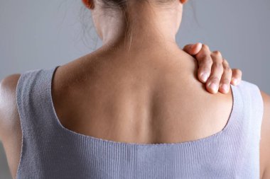 Asyalı kadının omuz ağrısı var. Başka bir elle acı çeken omuz tutan bir kadın. Vücut-kas problemi, sağlık ve ilaç sorunları olan insanlar..