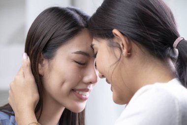 Genç memnun Asyalı lezbiyen kadınların gözleri kapalı ve gözyaşı damlaları birbirlerine dokunurken görüntüsü. Homoseksüel ilişki fikri, şefkat ve yakınlık. LGBT çift yaşam tarzı konsepti.