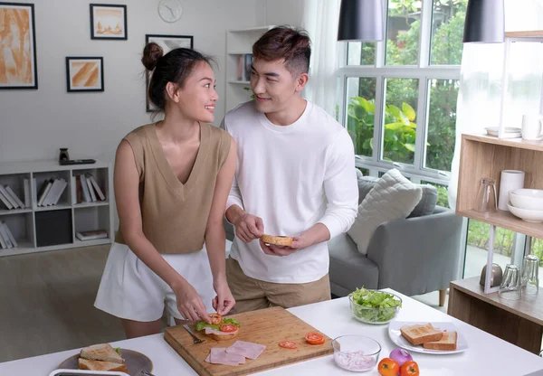 Romantic Asian couple is cooking on kitchen. Happy young man and young woman are having fun together while prepare food. Couple lifestyle concept.