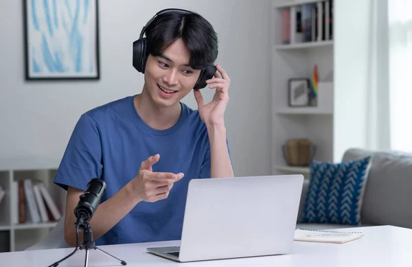 Feeling good happy and positive at work. Young Asian businessman wearing headset on video call with clients on laptop. Young Asian man giving online educational class lecture, consulting customer.