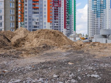 Önünde kum yığınları, beton halkalar ve Ukrayna 'nın başkenti Kyiv' de yeni renkli yüksek binalar ve inşaat ekipmanlarıyla bir inşaat sahası. Yeni bölge inşaat konsepti altında.