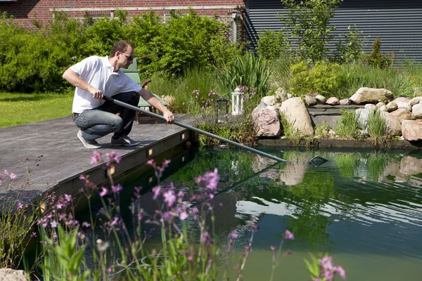 Homem limpa sua lagoa de jardim — Fotografia de Stock
