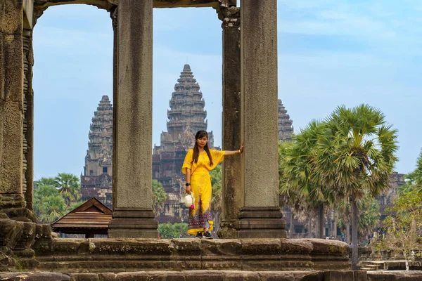 Kamboçya. Siem Reap Eyaleti. Angkor Wat Tapınağı önünde poz veren genç bir kadın. Kamboçya 'daki bir Budist ve tapınak kompleksi ve dünyanın en büyük dini anıtı.