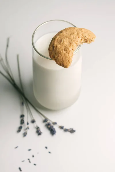 Bitten off cookie on glass of milk