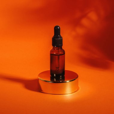 Turuncu arka planda yağlı koyu kehribar cam şişe. Cilt bakımı ürünü, C vitamini