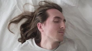 Genç yakışıklı adam yatakta uyuyor.