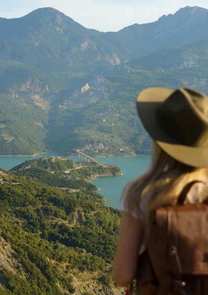 ビューポイントから湖や山の景色を見てバックパック付きの旅行者の女性のバックパックビュー 背景に焦点を当てる — ストック写真