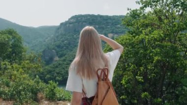 Kadın büyük manzaralı uçurum ve nehir manzarasına doğru yürüyor, el kamerasıyla çekilmiş..