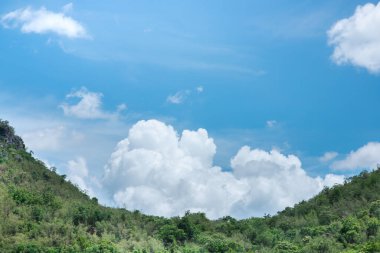 Arka plan için mavi gökyüzünün altında yeşil dağlar ve güzel gökyüzü bulutları, turizm konsepti