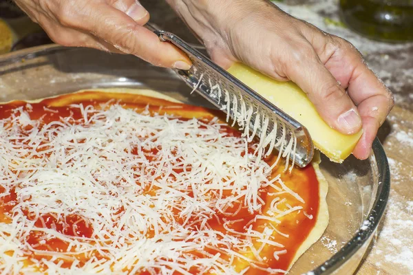 Mit der Reibe Käse in der Pizza reiben — Stockfoto