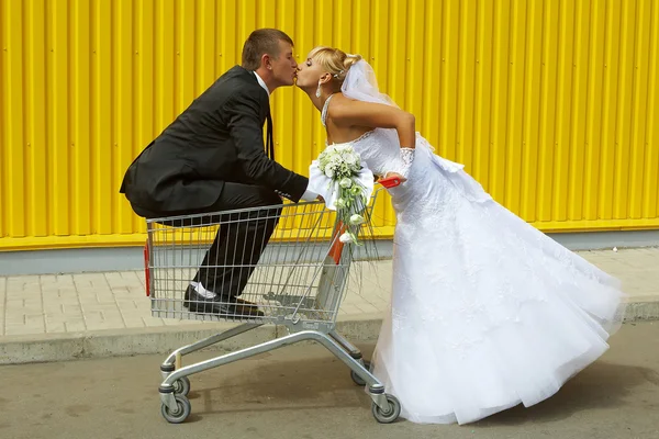 Bruid en bruidegom spelen met een mand van supermarkt — Stockfoto