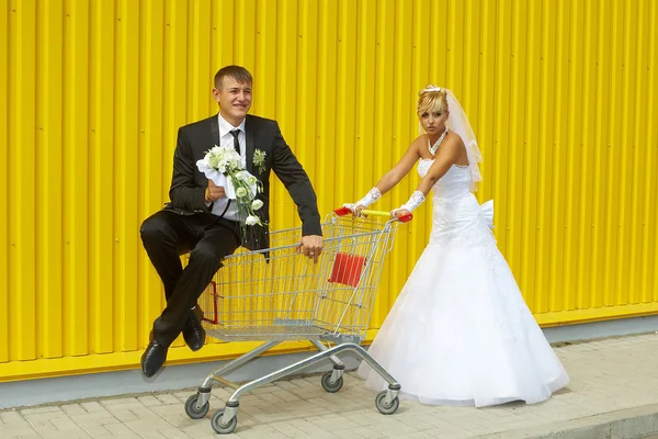 Sposa e sposo che giocano con un cesto di supermercato — Foto Stock