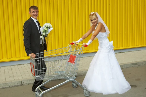 Bruid en bruidegom spelen met een mand van supermarkt — Stockfoto