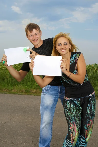 Grappige paar toont een leeg vel papier — Stockfoto