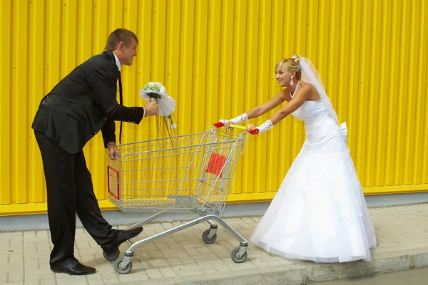 Bruid en bruidegom spelen met een mand van supermarkt — Stockfoto