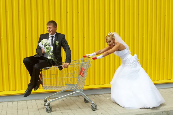 Bruid en bruidegom spelen met een mand van supermarkt — Stockfoto