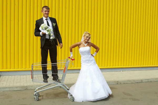 Bruden och brudgummen leker med en korg av stormarknad — Stockfoto