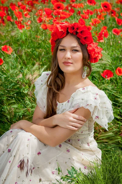 Wanita cantik duduk di bunga poppy — Stok Foto