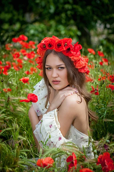 Schöne Frau sitzt in der Mohnblume — Stockfoto