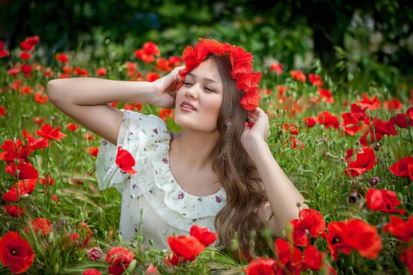 Hermosa mujer sentada en la flor de amapola — Foto de Stock