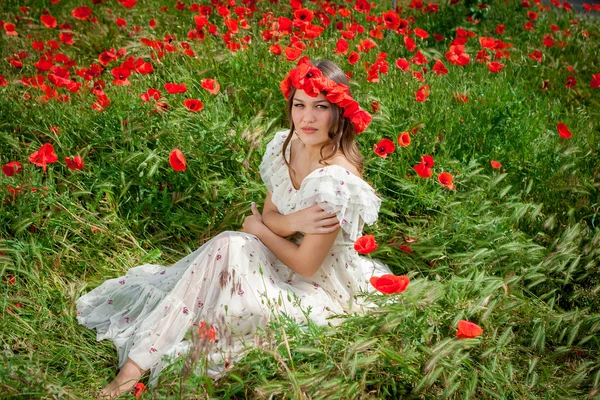 Mooie vrouw zitten in de papaver bloem — Stockfoto