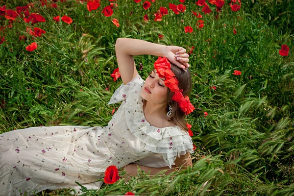 Hermosa mujer sentada en la flor de amapola — Foto de Stock