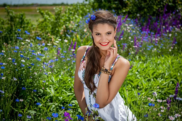 Vackra glad kvinna i de vilda blommor — Stockfoto