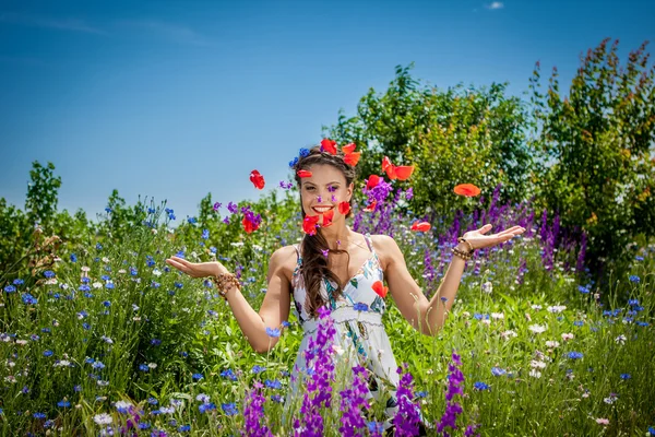 Vackra glad kvinna i de vilda blommor — Stockfoto