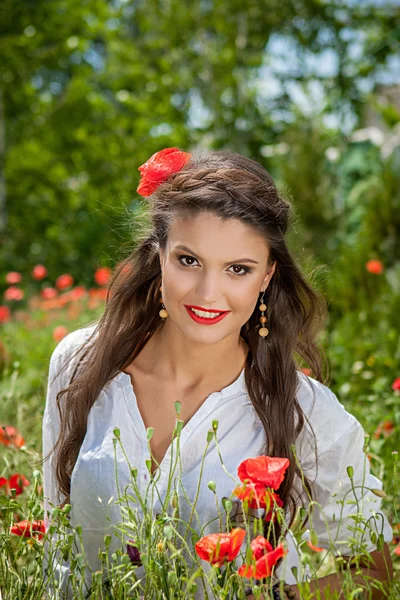 Wanita cantik yang duduk di bunga poppy — Stok Foto