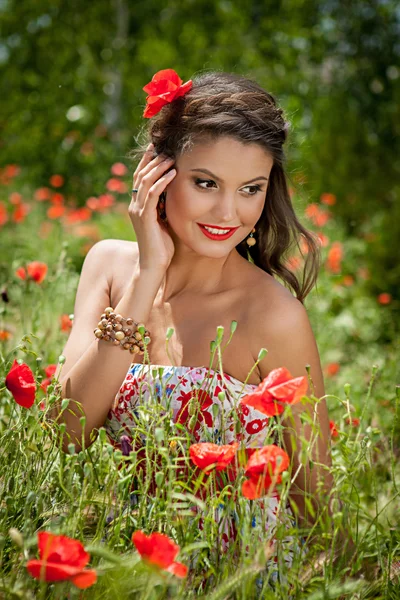 Piękna kobieta siedzi w maku kwiat — Zdjęcie stockowe