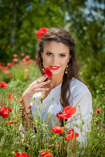 Piękna kobieta siedzi w maku kwiat — Zdjęcie stockowe