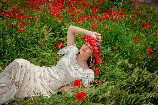 Hermosa mujer sentada en la flor de amapola — Foto de Stock