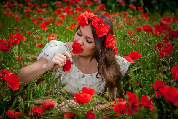 Vacker kvinna sitter i vallmo blomma — Stockfoto