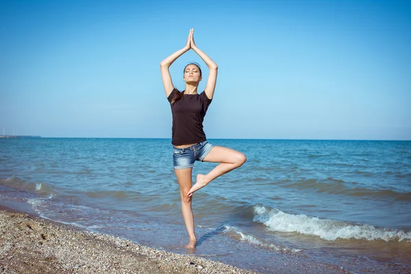 Young woman practicing yoga at seashore — Stock Photo, Image