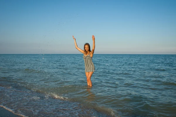 Jovem menina espirrando a água no mar — Fotografia de Stock