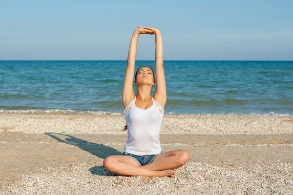 Mujer joven practicando yoga o fitness en la orilla del mar — Foto de Stock