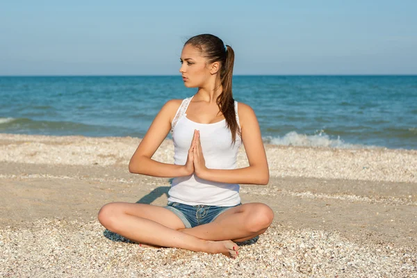 Young woman practicing yoga or fitness at seashore — Stock Photo, Image