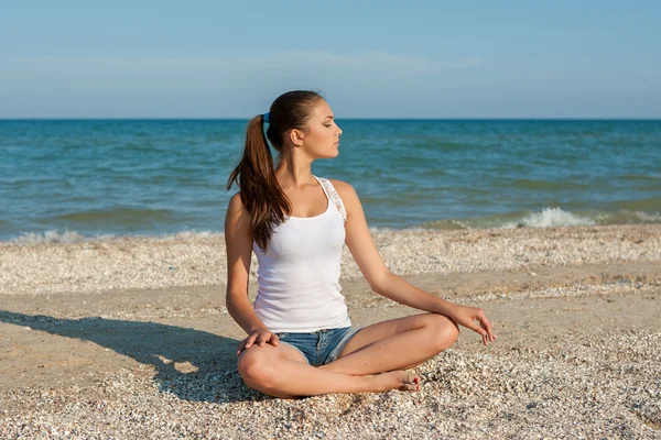 Young woman practicing yoga or fitness at seashore — Stock Photo, Image