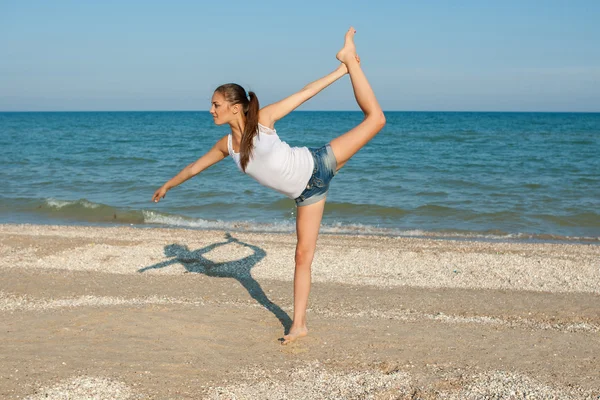 Young woman practicing yoga or fitness at seashore — Stock Photo, Image