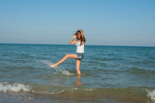 Jovem menina espirrando a água no mar — Fotografia de Stock