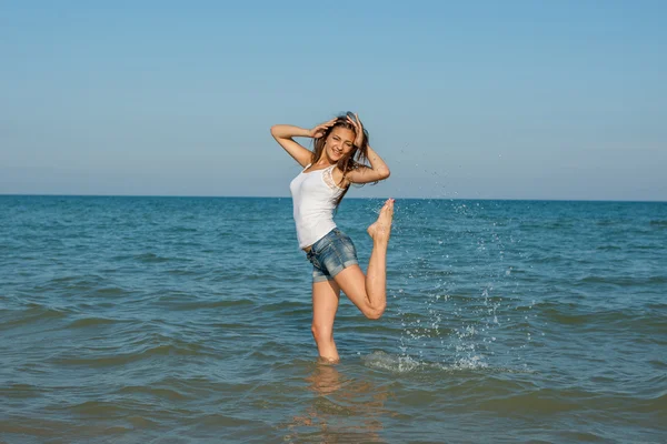 Young girl splashing the water in the sea — Stock Photo, Image